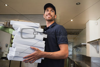 Smiling pizza delivery man holding many pizza boxes
