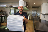 Smiling pizza chef holding stack of pizza boxes