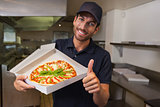 Happy pizza delivery man showing fresh pizza and thumbs up