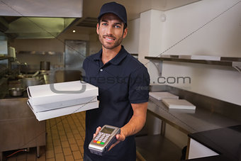 Smiling pizza delivery man holding credit card machine