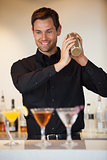 Happy bartender shaking cocktails