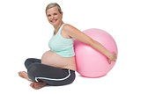 Pregnant woman leaning against pink exercise ball
