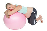 Cheerful pregnant woman kneeling against pink exercise ball