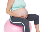 Pregnant woman sitting on pink exercise ball