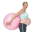 Pregnant woman holding pink exercise ball behind her back
