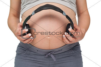 Pregnant woman holding headphones over bump