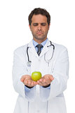 Serious doctor showing apple to camera