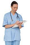 Concentrating nurse writing on clipboard