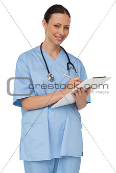 Happy nurse writing on clipboard