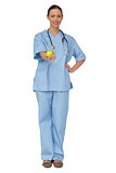 Smiling nurse in scrubs holding green apple