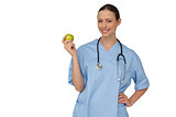 Happy nurse in scrubs holding green apple