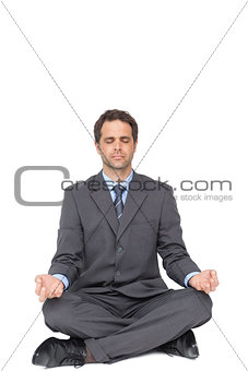 Peaceful businessman meditating in lotus pose