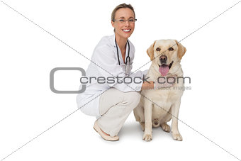 Pretty vet petting yellow labrador dog smiling at camera