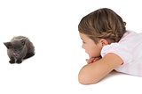 Cute girl looking at grey kitten lying on floor