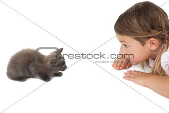 Cute little girl looking at grey kitten lying on floor
