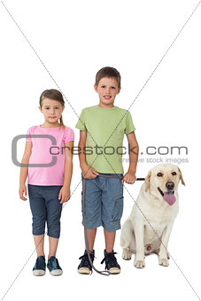 Cute siblings smiling at camera with their labrador dog