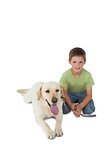 Cute little boy kneeling with his labrador dog smiling at camera