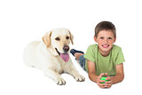 Cute little boy holding ball lying on floor with his labrador