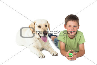 Cute little boy holding ball lying on floor with his labrador