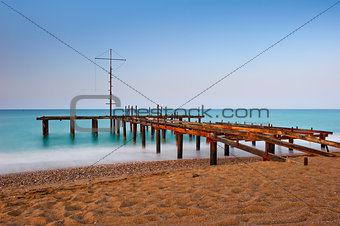 rusty skeleton of the old pier and turquoise sea