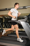 young man running at treadmill in gym