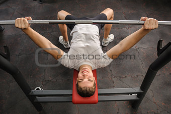 young man doing bench press workout in gym
