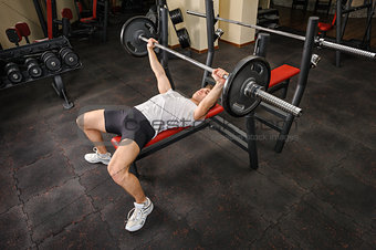 young man doing bench press workout in gym