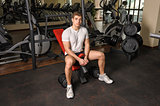 young man sits after workout in gym