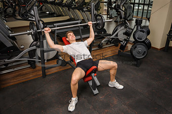 Young man doing Barbell Incline Bench Press workout in gym
