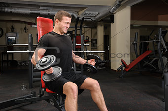 Young man doing Dumbbell Biceps workout in gym