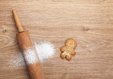 Rolling pin with flour and gingerbread cookie on wooden table