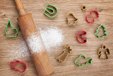 Rolling pin with flour and cookie cutters on wooden table