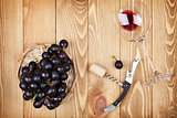 Red wine glass, corkscrew and grape