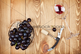 Red wine glass, corkscrew and grape