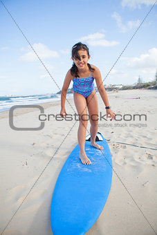 Cute young girl standing on surfboard