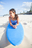Cute young girl lying on surfboard
