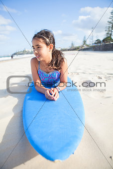Cute young girl lying on surfboard