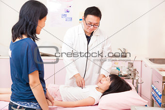 pediatrician examining little girl on the bed