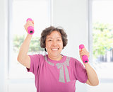 happy senior woman working out with dumbbells at home