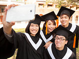 group of graduates  taking picture with cell phone