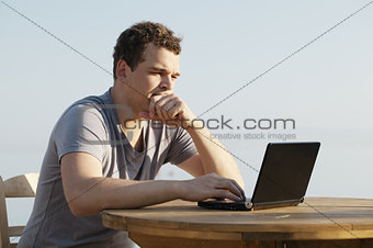 Man typing on a small laptop computer