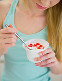 Closeup on young woman eating yogurt