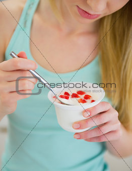 Closeup on young woman eating yogurt
