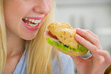 Closeup on young woman eating sandwich
