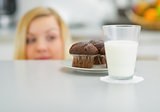 Closeup on chocolate muffin and young woman looking out from tab