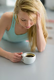 Young woman having cup of coffee in kitchen after sleep