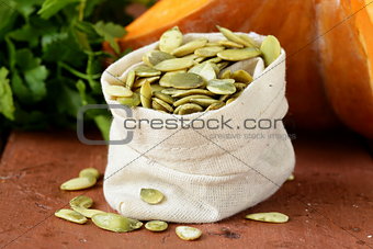 peeled pumpkin seeds and fresh pumpkin on a wooden table