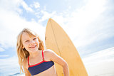 Happy young girl with surfboard at beach
