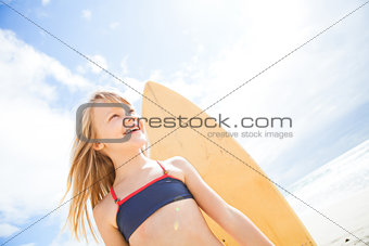 Happy young girl with surfboard at beach