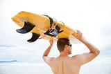 Man resting surfboard on head at beach